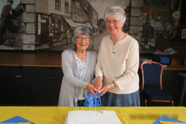 Two women cutting a cake 