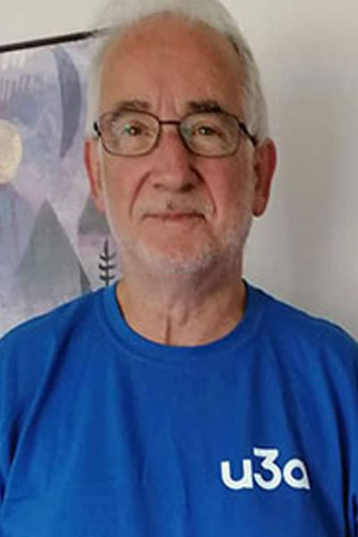 A man in a blue t-shirt with the u3a logo on, smiling.