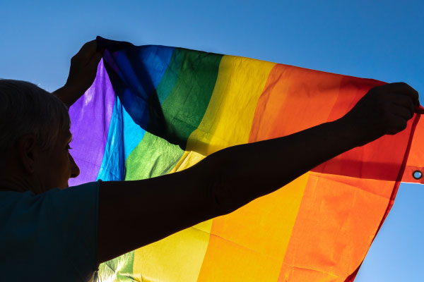 A woman is holding a rainbow flag.