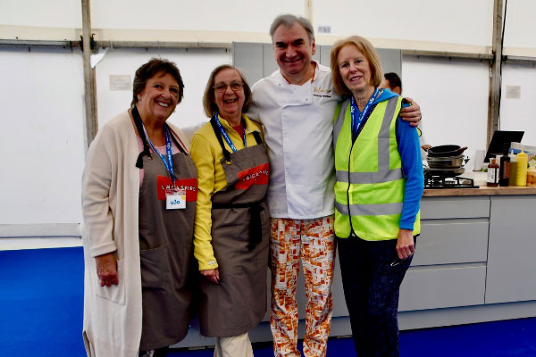 Three women and a man wearing chef trousers smiling