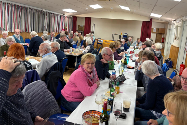 A room with large tables - people have just eaten dinner and are chatting