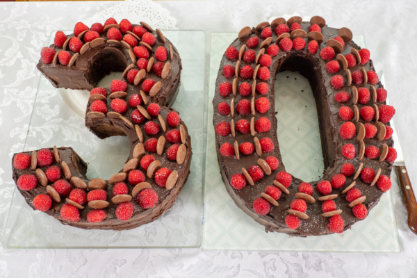 cake in the shape of the number 30 with chocolate buttons and raspberries
