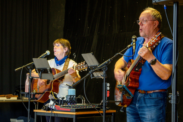 a man and a woman play guitar and sing on stage
