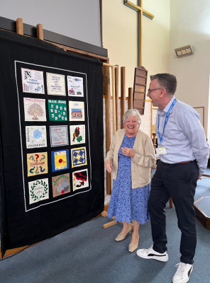 two people laugh by a tapestry