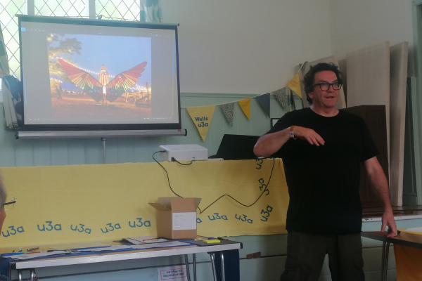 man giving presentation showing photo of stained glass wings