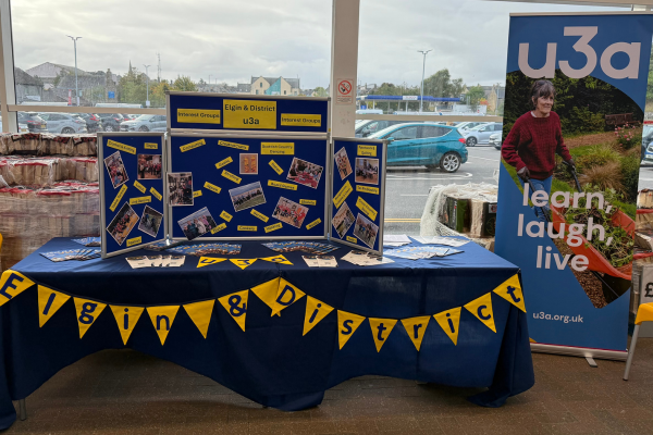 an information stand decorated with yellow bunting and a standing poster