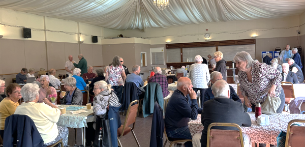 many people sat around tables in a large room